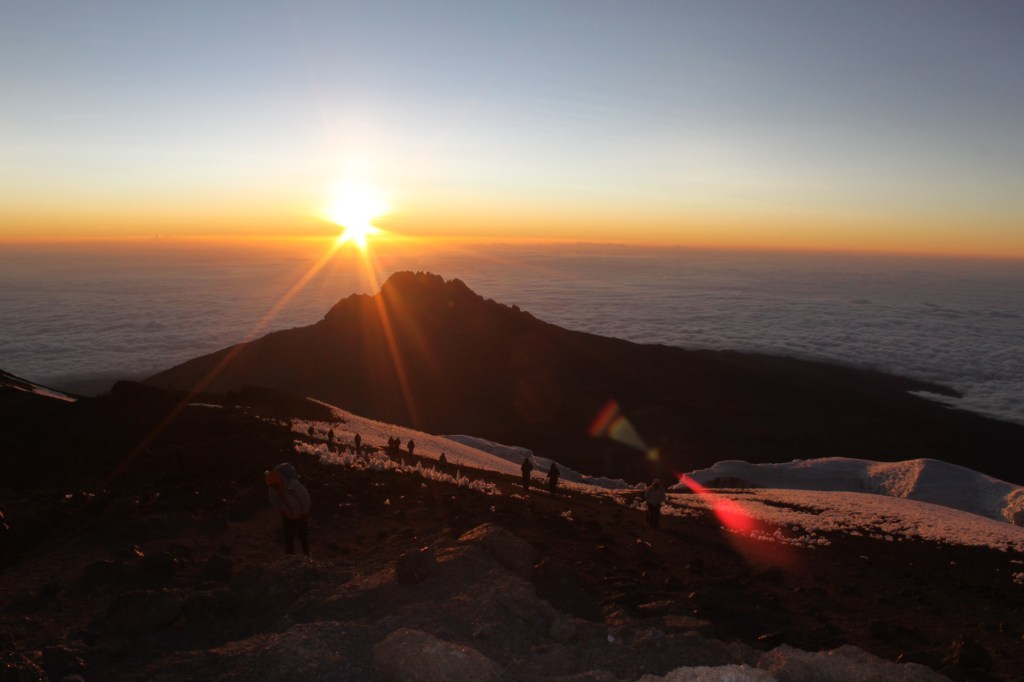 Sunrise peaks out over the tip of Mt Kilimanjaro in Tanzania, over a wall of cloud. 